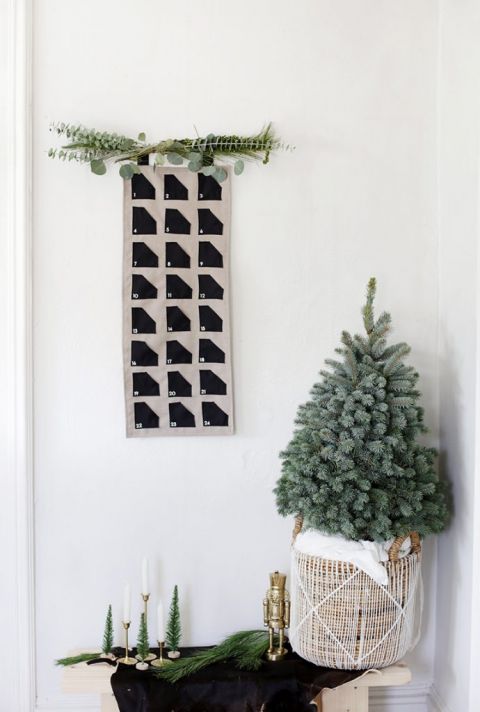 fabric advent calendar on wall above mini Christmas tree in basket
