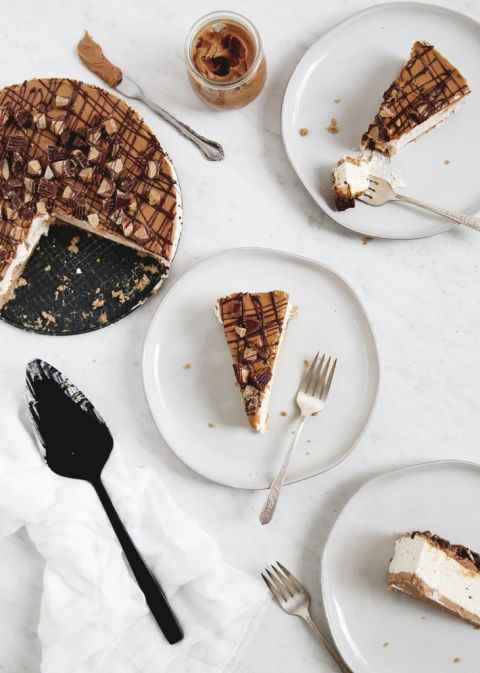3 slices of peanut butter cheesecake on white plates next to cheesecake and black serving spoon