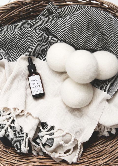 basket with towel, dryer balls and essential oils bottle in it