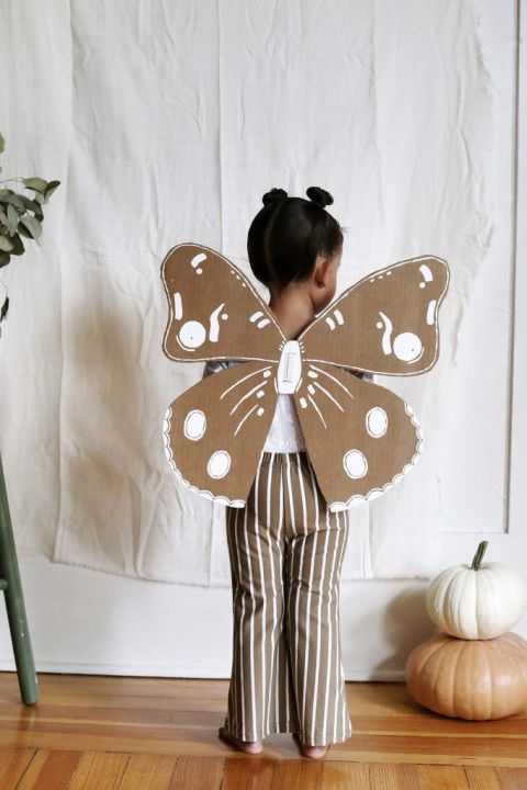 little girl in cardboard moth wings costume