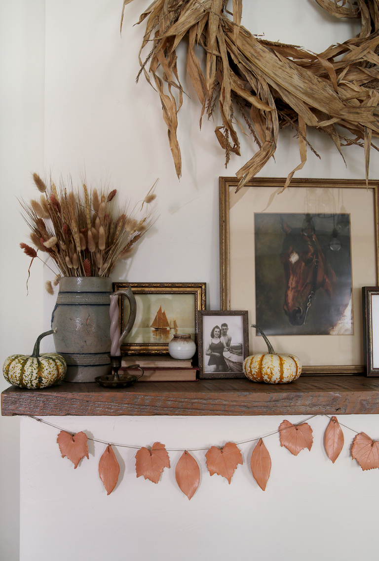 clay leaf garland hanging from wood mantel with fall decor on mantel