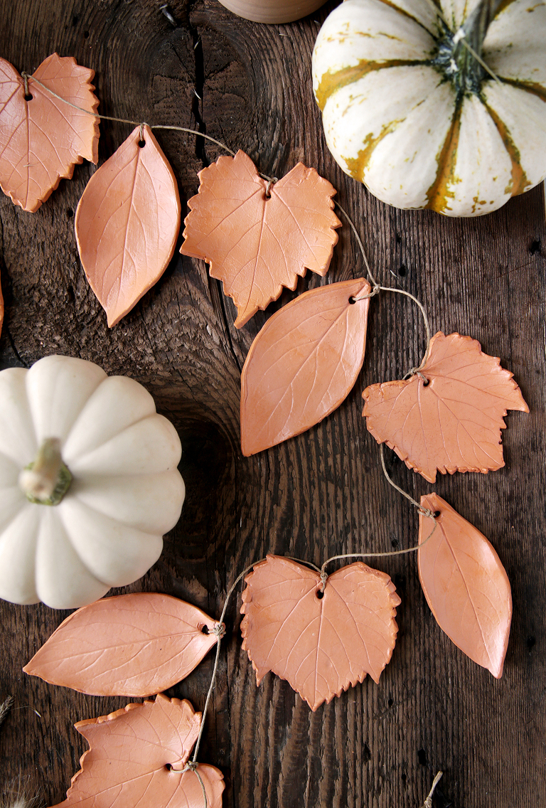 terracotta clay leaf garland laying on wood board with mini pumpkins