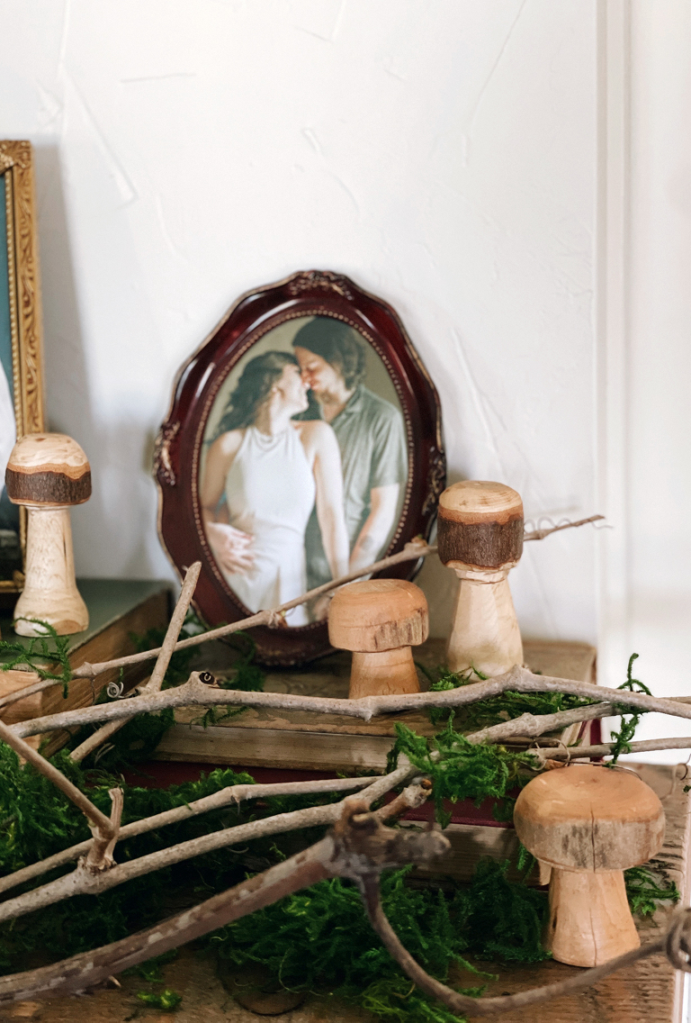 vintage picture frame surrounded by moss branches and hand carved wood mushrooms
