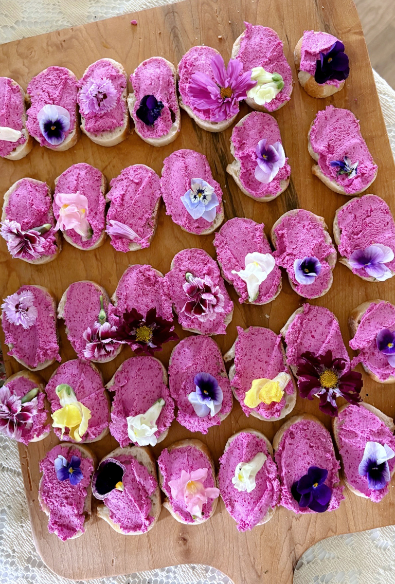 roasted beet whipped feta goat cheese crostini with edible flowers on wood platter