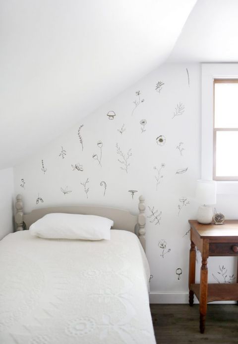 twin bed in white room with painted floral accent wall