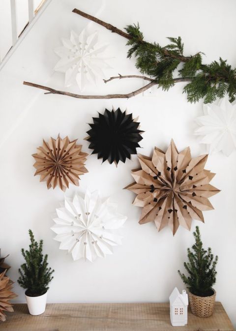white wall with branch with greenery and paper bag stars hanging on branch