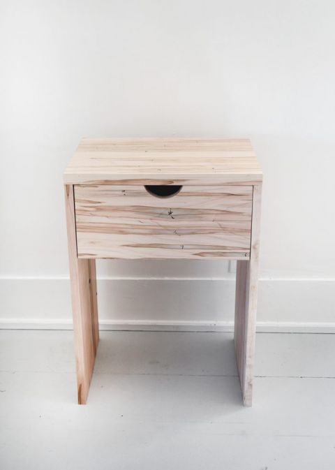 wood nightstand with drawer against white wall