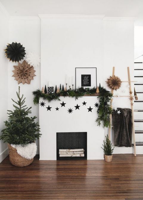 fireplace with little tree in basket and greenery and stars on mantel