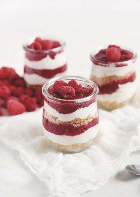 glass jar of raspberry cheesecake layered with raspberries on top