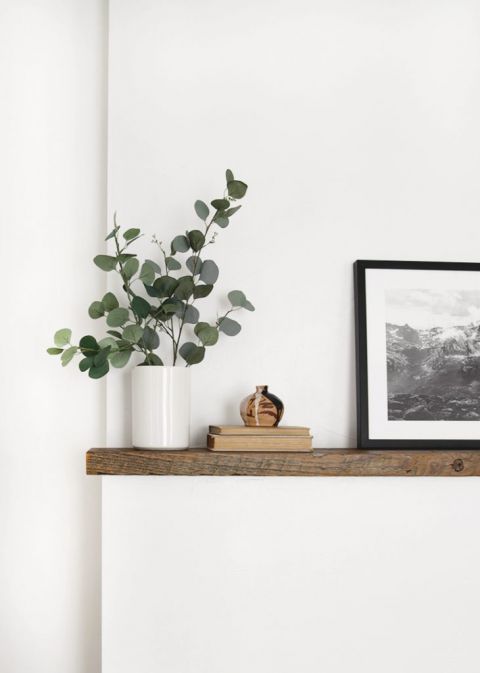 wood mantle white wall with eucalyptus in vase