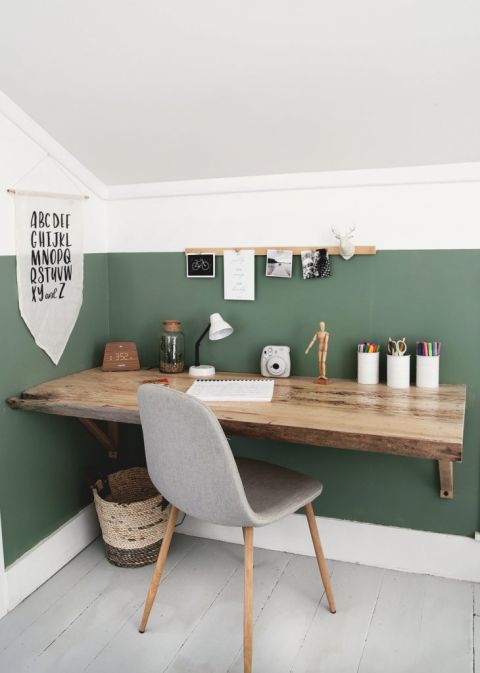 wood desk against green wall with gray chair