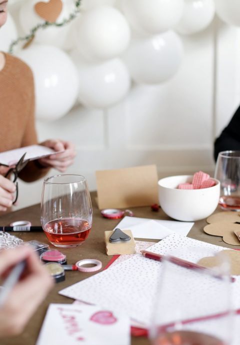 table with wine glasses and valentines day card supplies