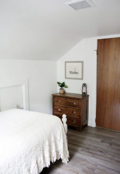 corner of white room with wooden dresser and decor