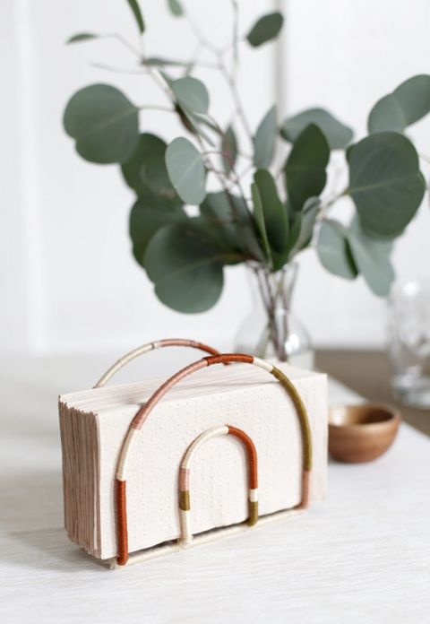 rainbow napkin holder with light pink napkins in front of eucalyptus