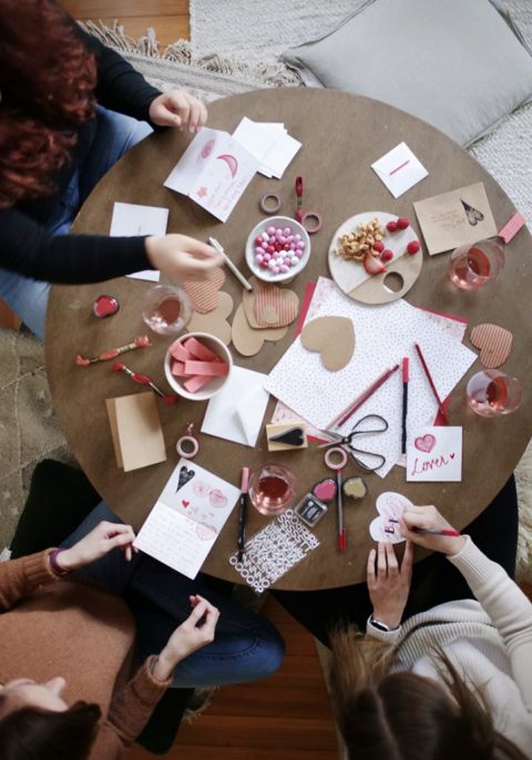 overhead shot of coffee table with people making valentines day cards