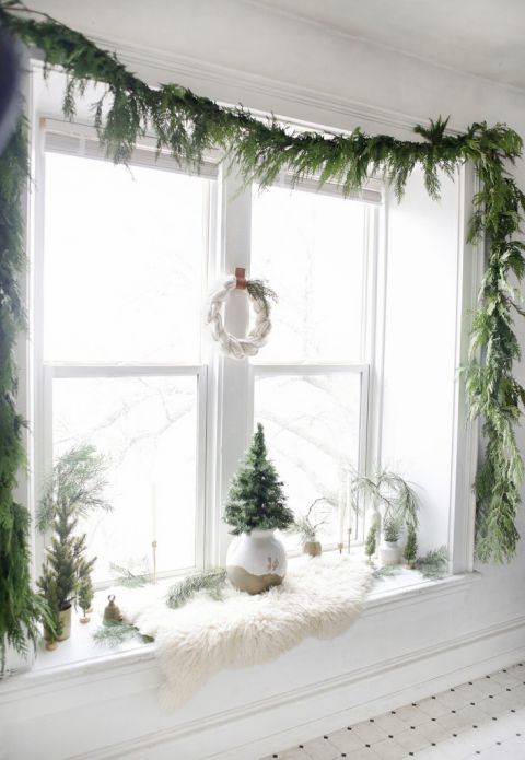 window with greenery garland around edges and Christmas decor inside