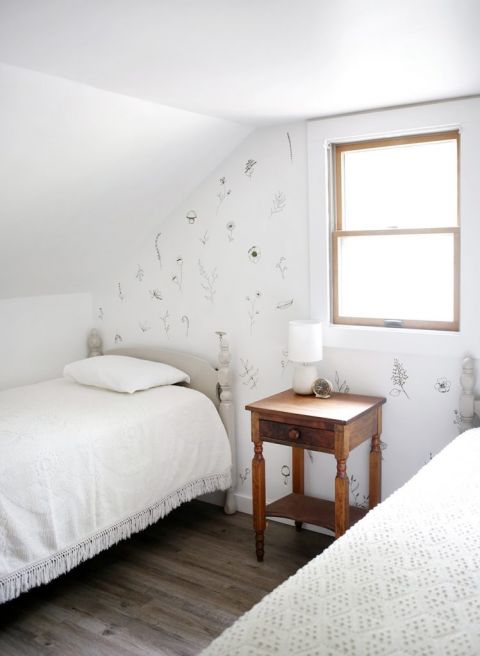 twin bed in white room with painted floral accent wall