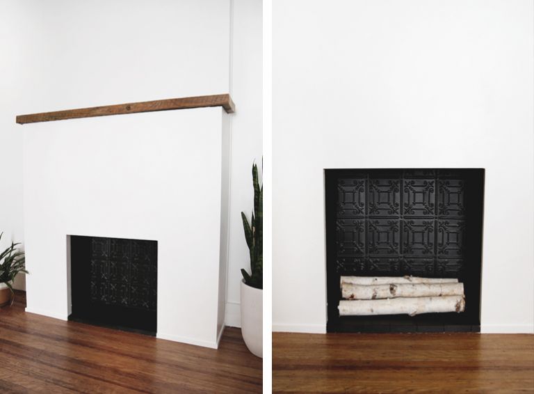 white fireplace surround with wood mantle, black firebox with birch logs