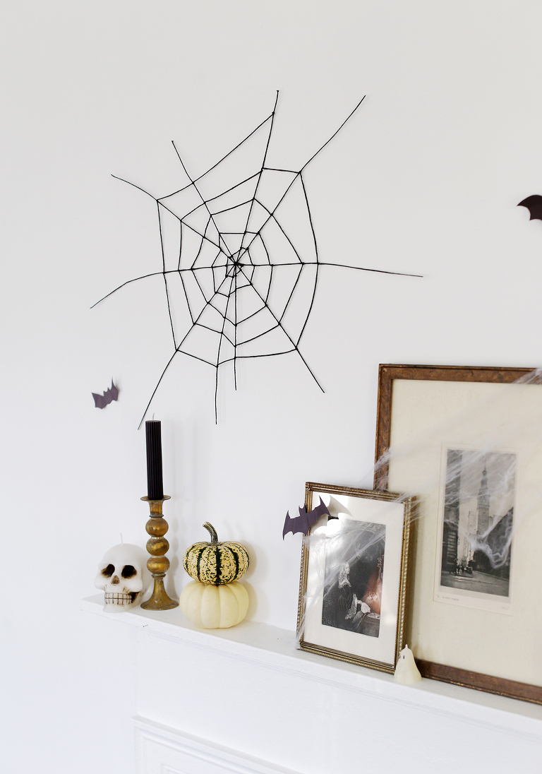 black spider web decor hanging on white wall above mantel