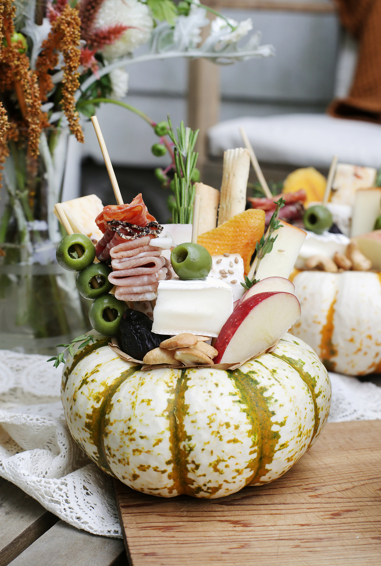 charcuterie arranged inside a carved out mini pumpkin