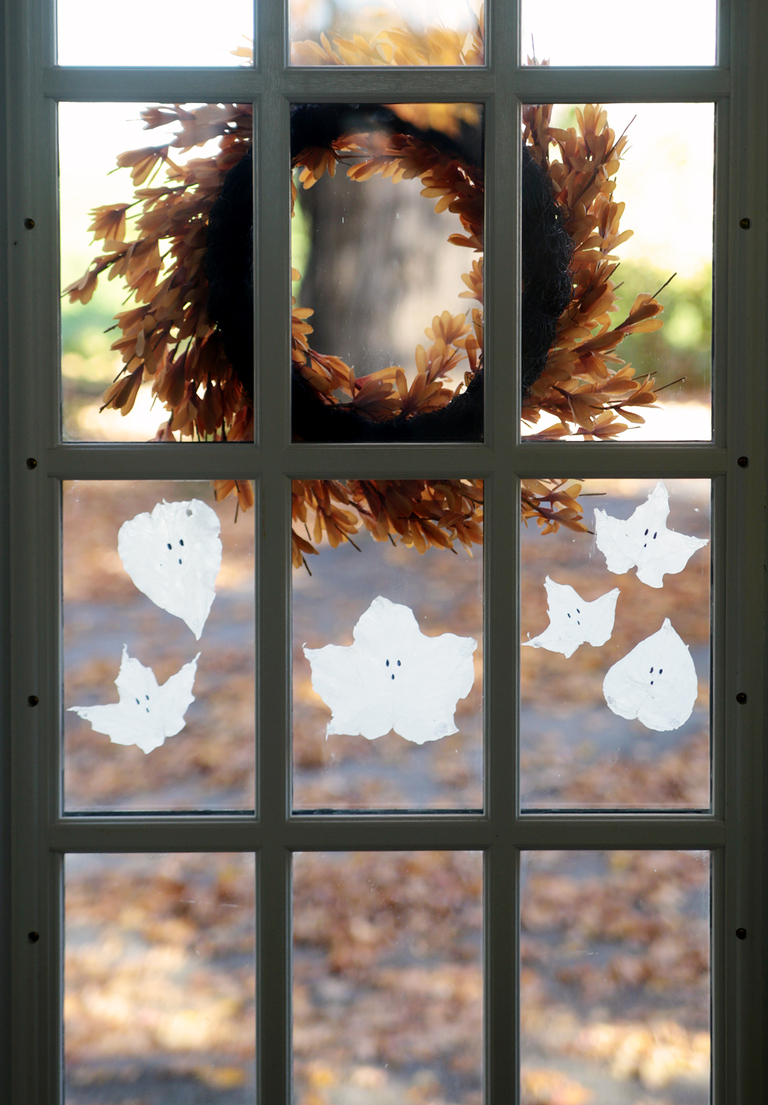 back view of window with fall wreath hanging on it and glue ghost leaves on the window