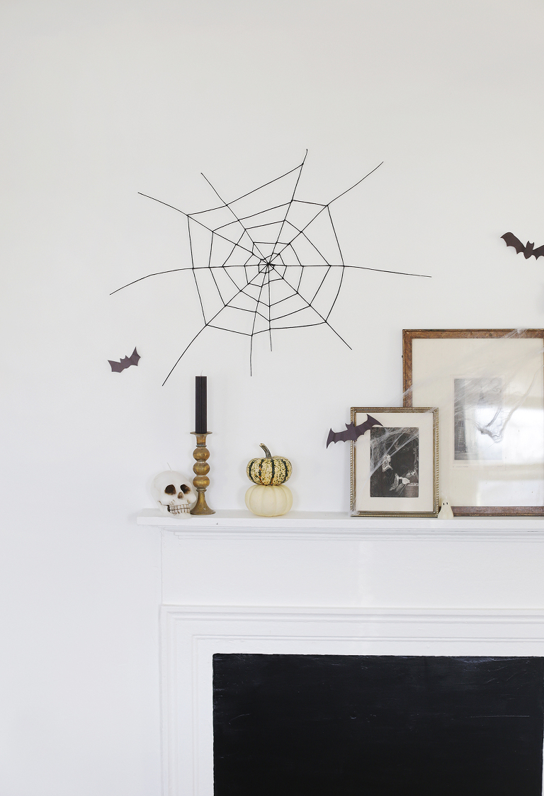 black spider web decor hanging on white wall above mantel