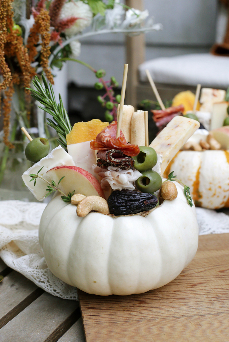 charcuterie arranged inside a carved out mini pumpkin