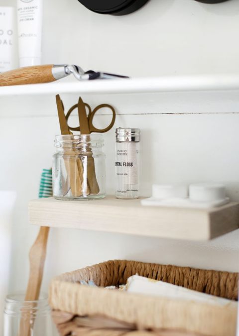 small wooden shelf inside white medicine cabinet with toiletries