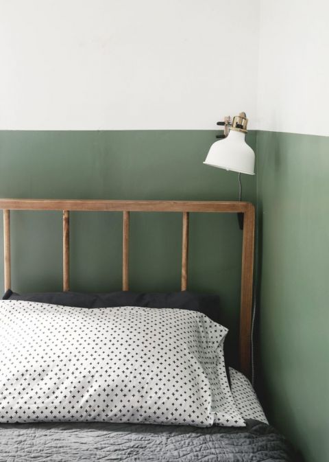 diy wood dowel bed against green and white wall with white lamp over bed