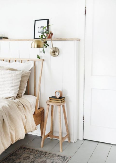 wood stool next to wood headboard against white wall