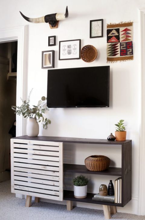 slatted black console table under gallery wall and tv