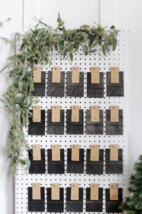white pegboard with black and brown envelopes and eucalyptus hanging from it