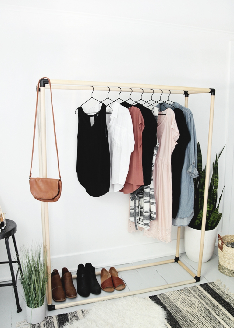 black and wood dowel clothing rack with clothes on it