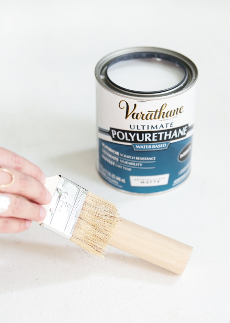 can of polyurethane and paint brush on dowel