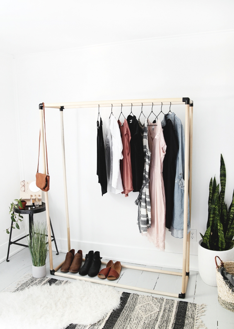 black and wood dowel clothing rack with clothes on it