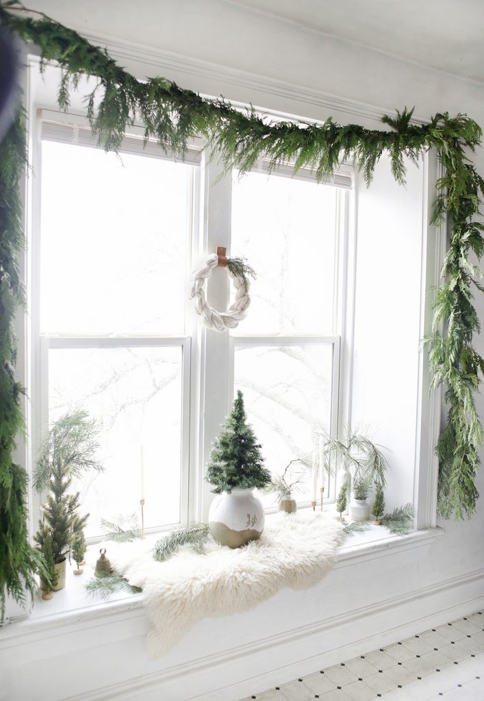 window with greenery garland around edges and Christmas decor inside