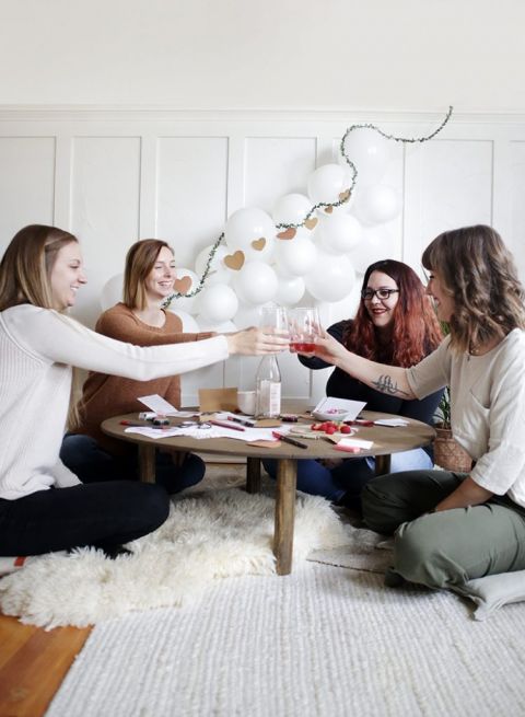 girls around coffee table cheersing glasses