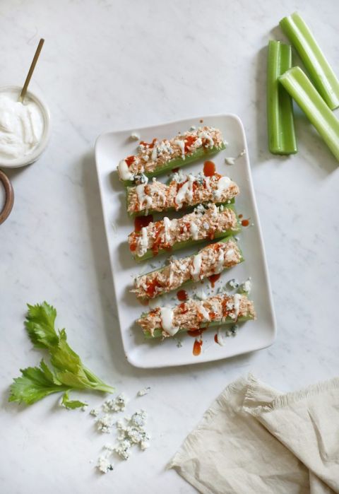 plate of celery with buffalo chicken on top surrounded by ingredients