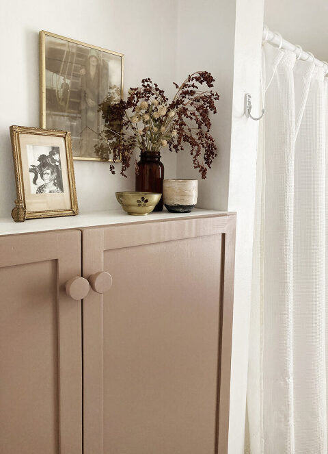 pink white cabinet doors with gold and natural decor on top of shelf