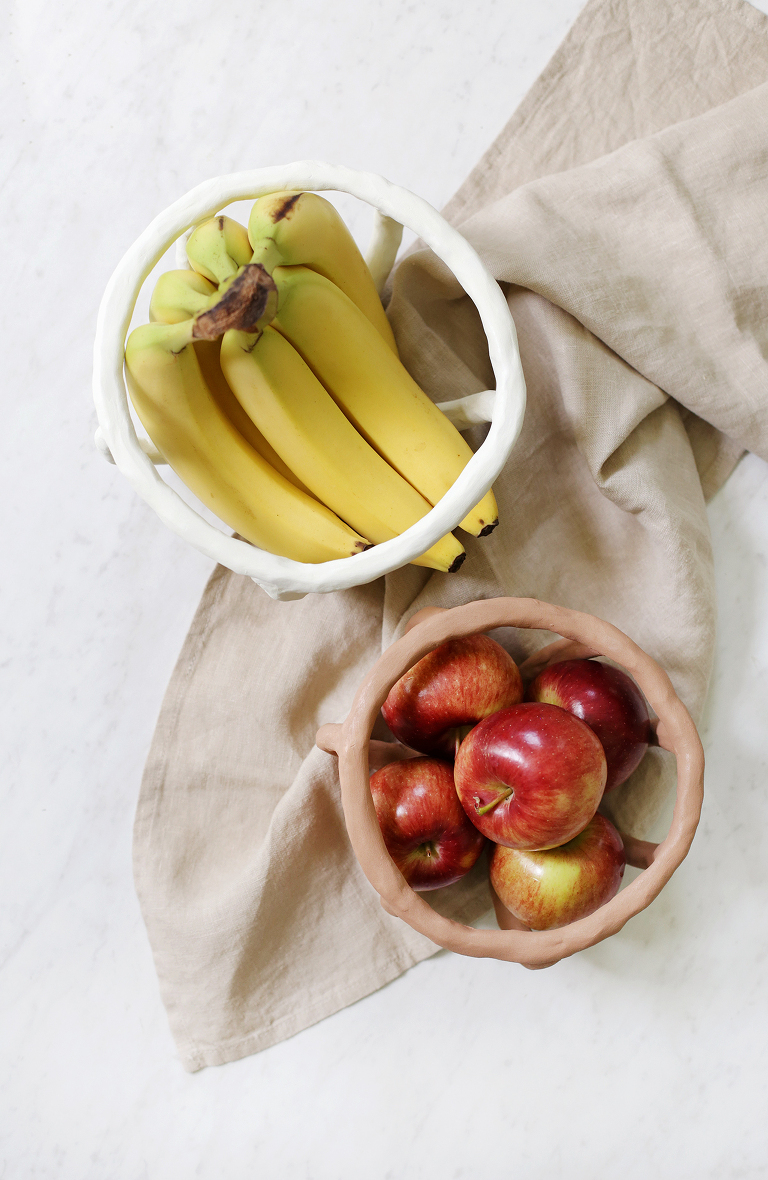 overhead shot of clay fruit bowls with fruit on top of linen towel