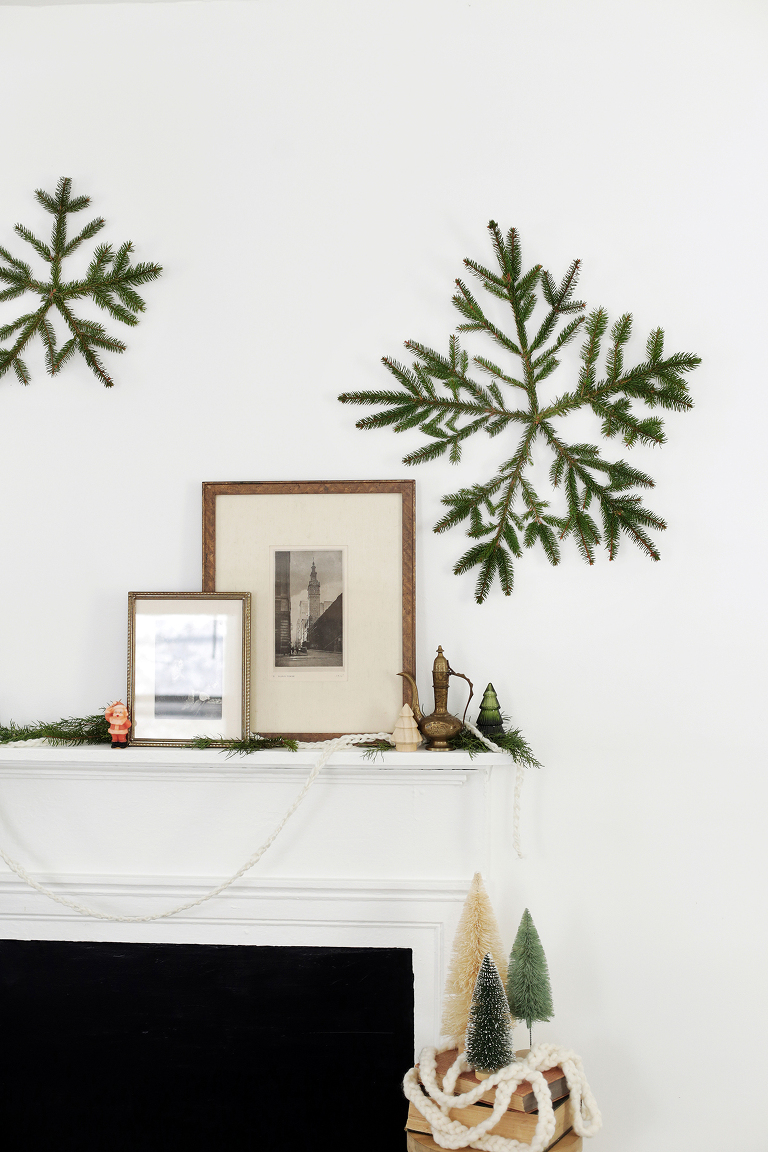 large pine snowflake over mantle with vintage frames and christmas decor