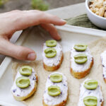 hand reaching for a piece of olive crostini on a platter