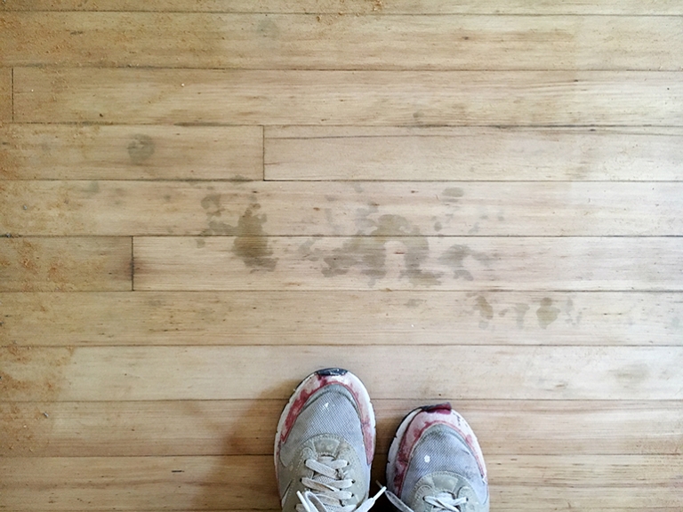 feet standing on hardwood floors with dark spots on wood