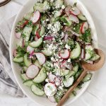 oval dish with cucumber radish salad with wooden spoon