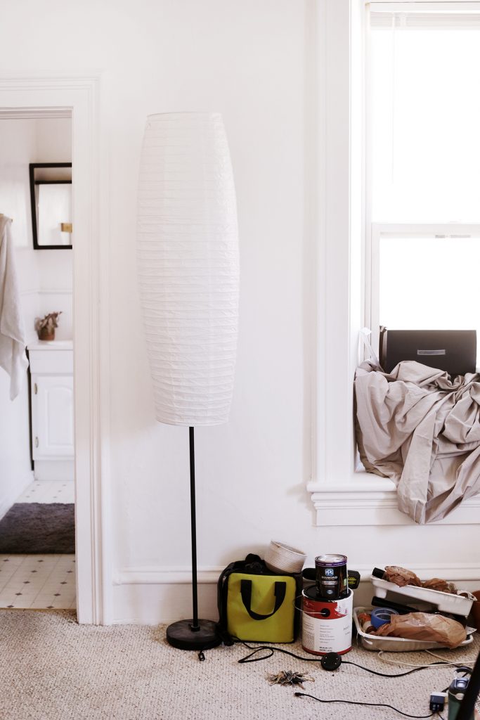 lamp and a bunch of tools and paint supplies in front of a white wall