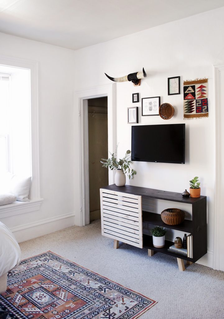 slatted black console table under gallery wall and tv