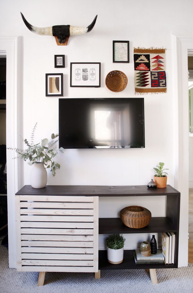 slatted black console table under gallery wall and tv