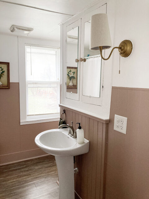 white pedestal sink beneath large mirrored medicine cabinet