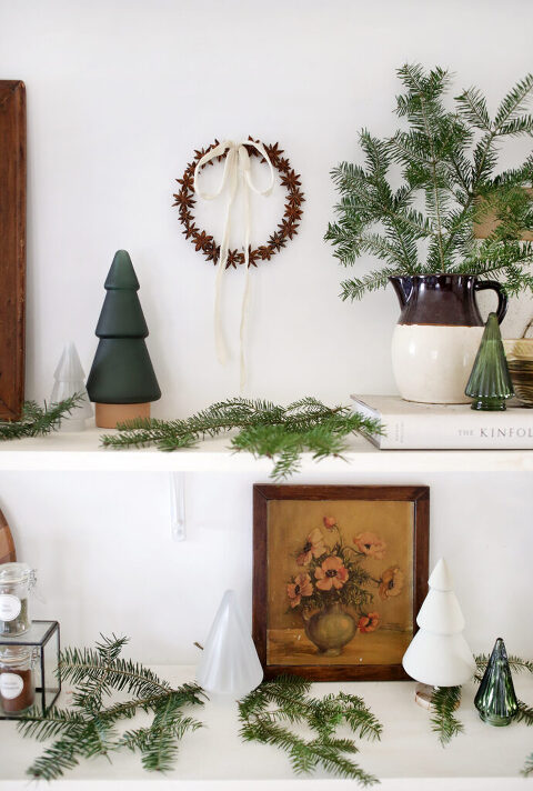 small wreath hanging on wall whilom shelves decorated with christmas and vintage decor
