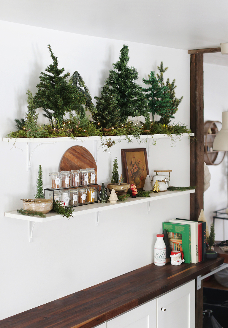 kitchen open shelving with spices and christmas decor and collection of small pine trees